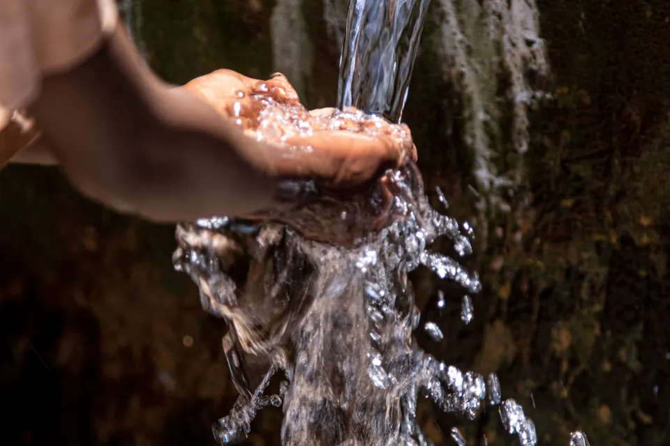 Fresh water flowing from an outdoor pipe into hands